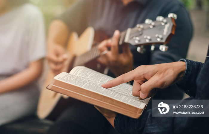 A young boy reads the Bible while his friend plays the guitar. when he worships God A small group of Christians or concepts in a church at a church.