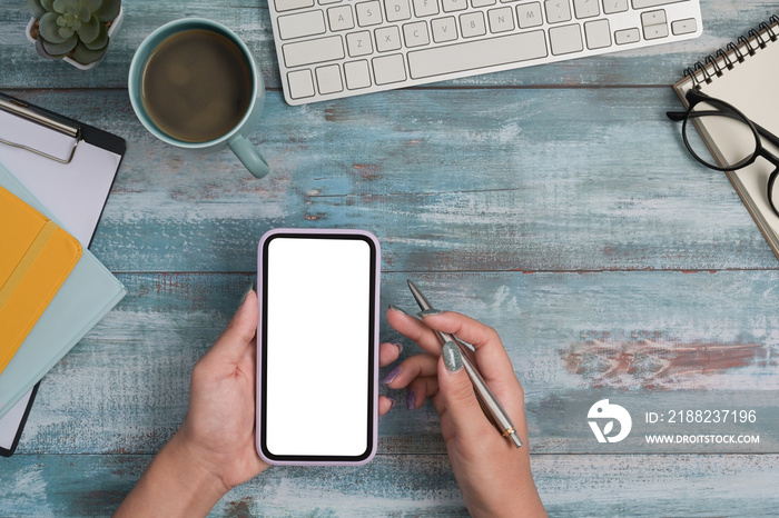 Overhead view woman using smart phone on wooden background. Flat lay.