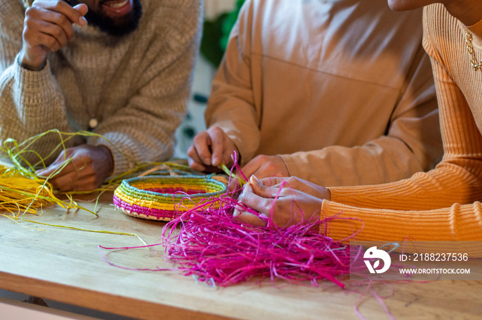 Two men and woman weaving baskets