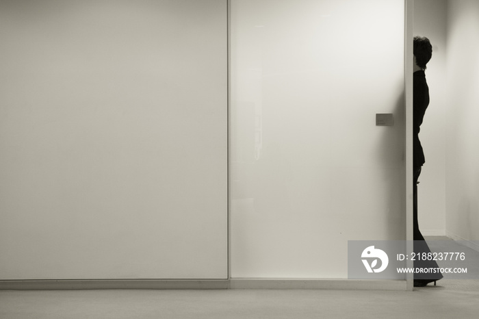 Woman standing in doorway of frosted glass conference room