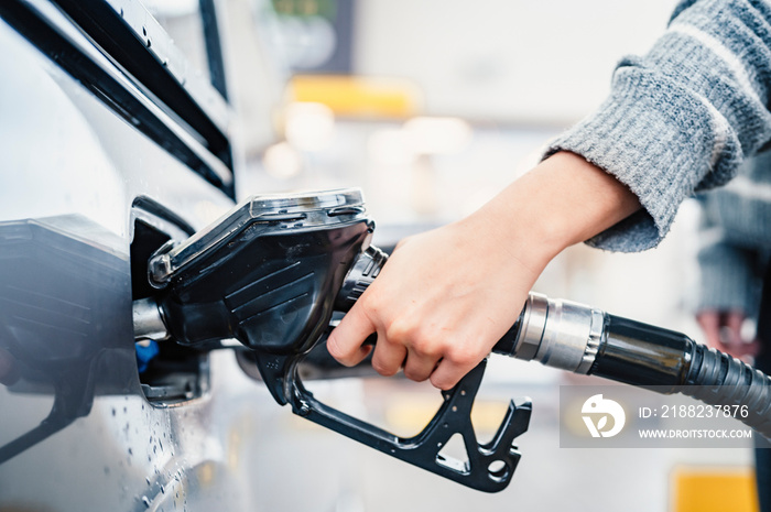 Closeup of woman pumping gasoline fuel in car at gas station. Petrol or gasoline being pumped into a motor. Transport concept