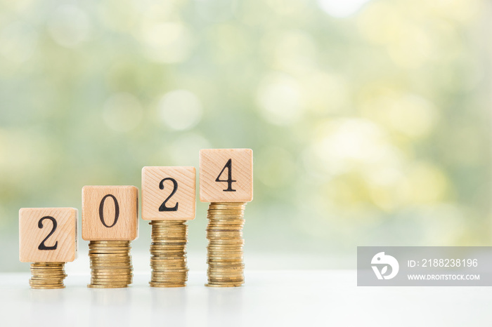 stack of coins on wooden table with new year message 2024 business growth new beginning