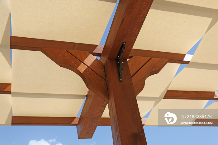 summer ceiling of wooden beams and white fabric and blue sky