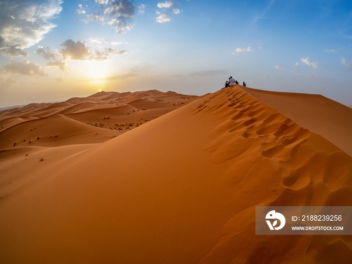 Turistas observando el atardecer entre las dunas del desierto