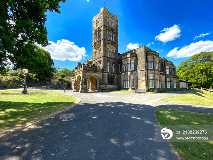 Cliffe Castle museum, in the local public park, with lawns, old trees, and a blue sky in, Keighley, Yorkshire, UK