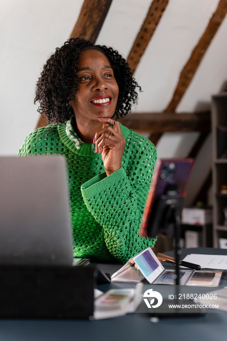 Smiling businesswoman looking away while working on laptop in office