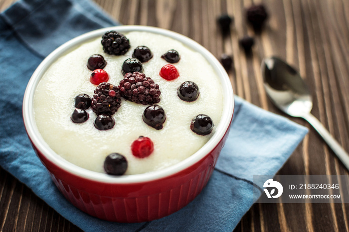 Semolina porridge with raspberries on rustic wooden background