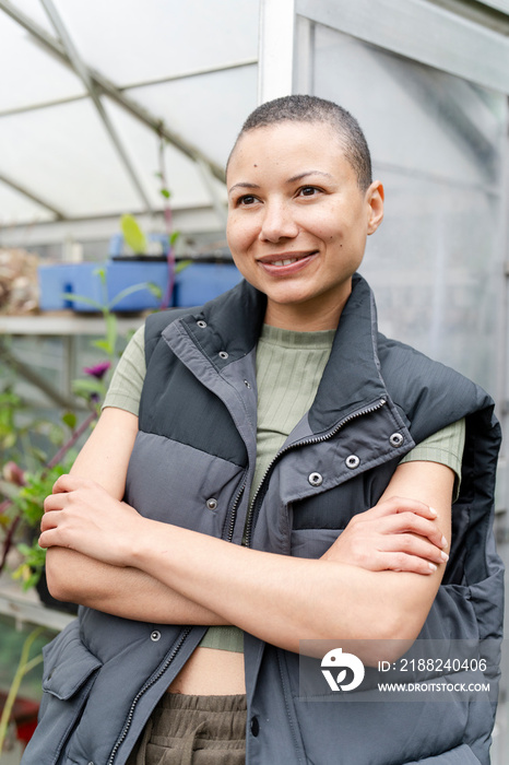 Portrait of smiling woman standing in front of greenhouse