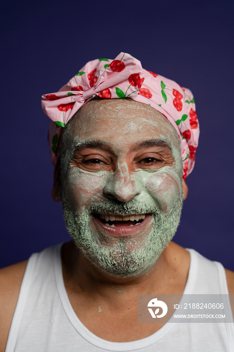 Portrait of man in facial mask and hair cap against purple background