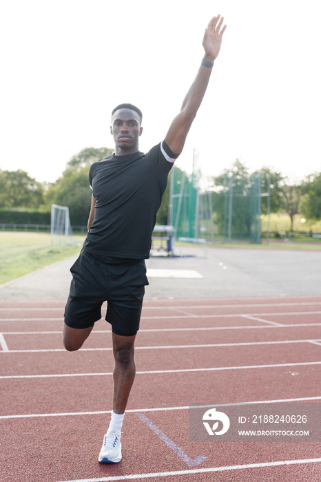 Athlete stretching leg before training at sports track