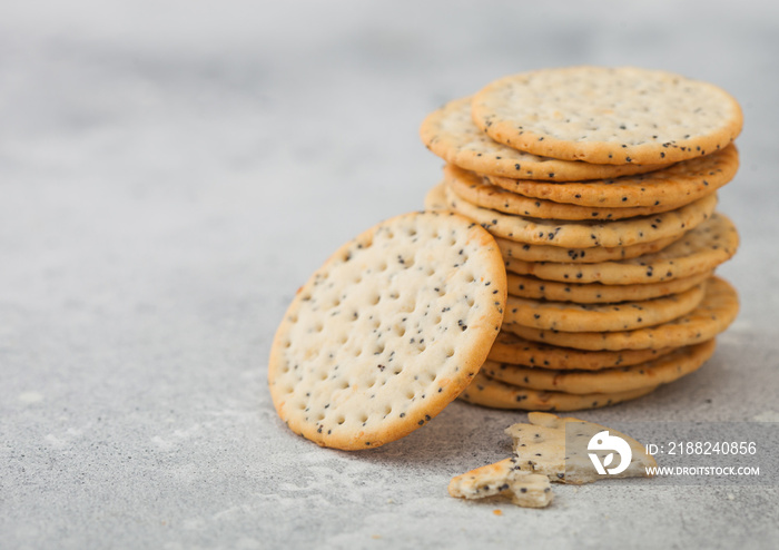 Stack of various organic crispy wheat flatbread crackers with sesame and salt on light kitchen table background.