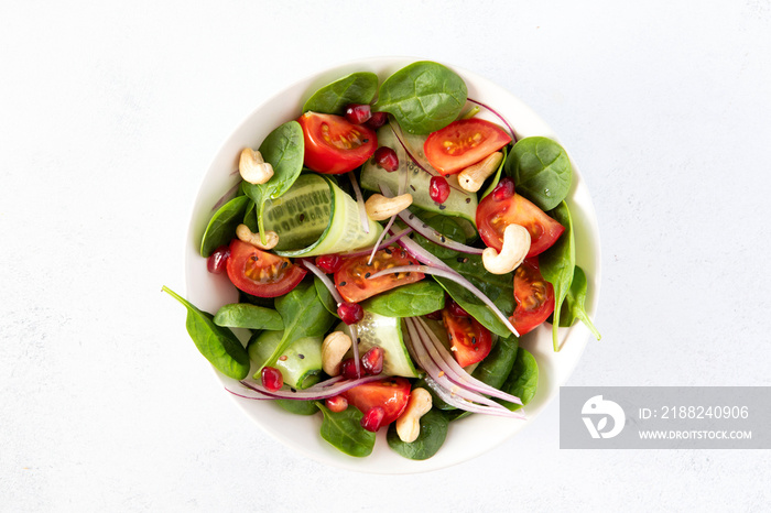 Healhty vegan lunch bowl with salad with spinach, tomato, cucumber, onion, cashew nuts, pomegranate and sesame with olive oil