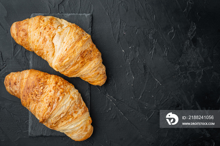 Fresh homemade baked golden brown croissant, on black stone background, top view flat lay, with copy space for text