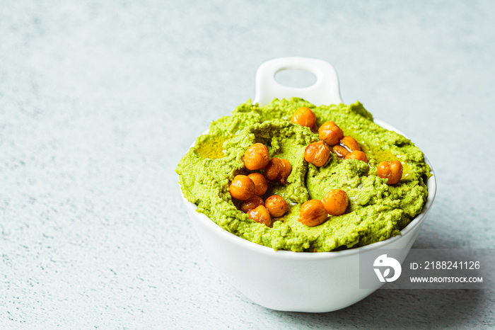 Green hummus in white bowl. Vegan chickpea dip. Healthy vegetarian food concept.