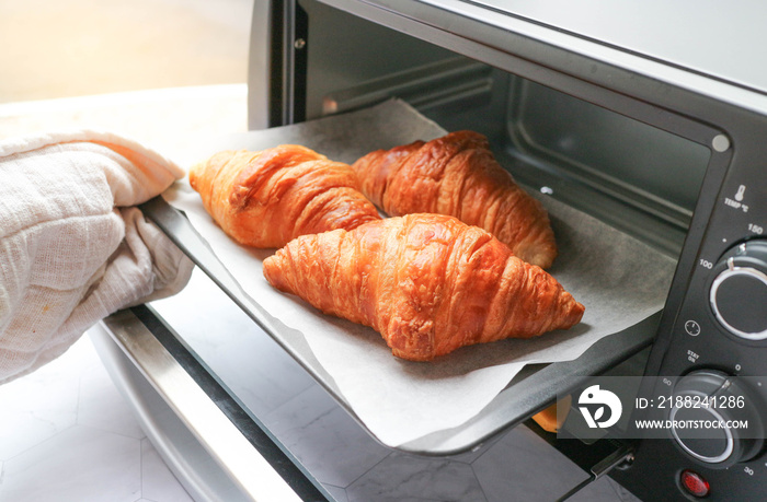 Croissant was taken out from mini oven ready to serve - Morning breakfast concept