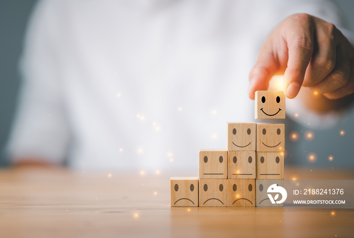 Customer service and Satisfaction concept ,Business people show a feedback with smile face wood cube happy Smiley face icon to give satisfaction in service. rating very impressed.