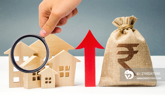 Money bag with arrow up and miniature wooden houses. The concept of rising property prices. High mortgage rates. Expensive rental apartment. Growing demand for home purchase. Indian rupee (rupiah)