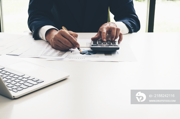 Businessman analyzing report on chart with calculator in office