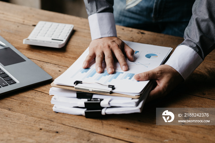 Businessman holding a pile of company financial documents, he is checking company finances before attending a meeting with the finance department. Concept of corporate financial management.