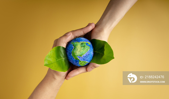 World Earth Day Concept. Green Energy, ESG, Renewable and Sustainable Resources. Environmental and Ecology Care. Hands of People  Embracing Green Leaf and Handmade Globe