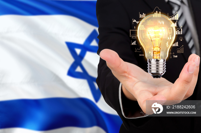 Israel creativity concept. Businessman with a light bulb in his hand on national background. Innovation and technology theme.