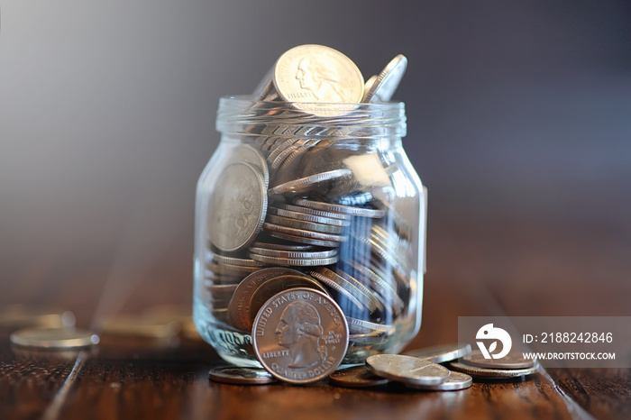 Coins in a glass jar on a wooden floor. Pocket savings from coin