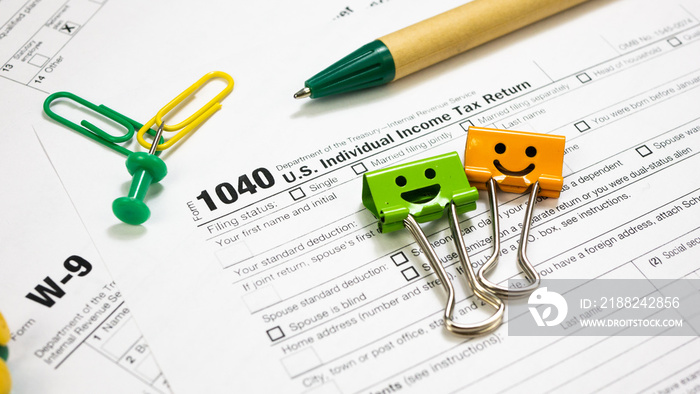 IRS 1040 and W-9 U.S. Tax Forms with smile binder clips, pen and clips. Wage statement and tax time concept