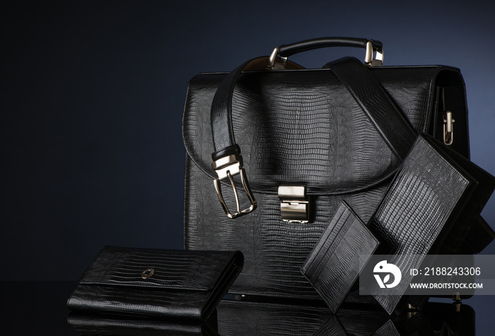 Fashionable men’s set of leather accessories on a dark background. Briefcase, wallet, belt