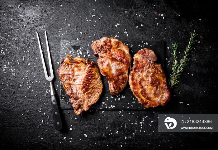 Grilled pork steak with a sprig of rosemary.