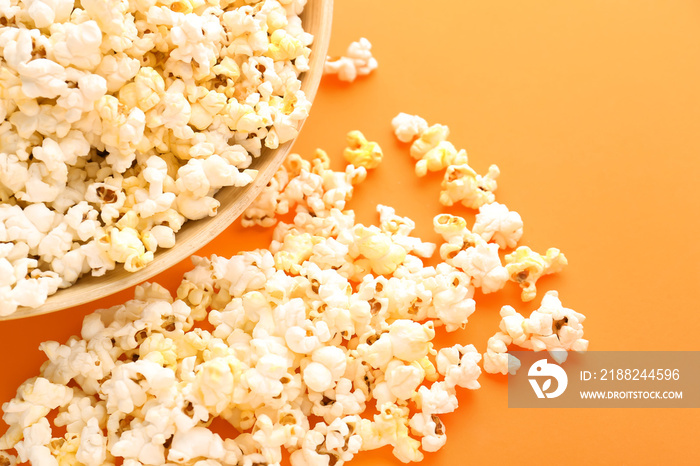 Bowl of delicious popcorn on color background, closeup