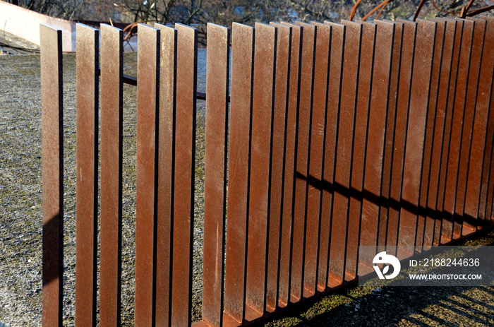 rusty sheet metal railing of individual strips at the top freely in space. spiral staircase with bars and full sheets of low fence in the city garden near the cafe in the park. sunny winter day