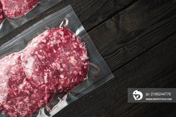 Burger meat vacuum sealed ready for sous vide cooking, on black wooden table background, top view flat lay, with copy space for text