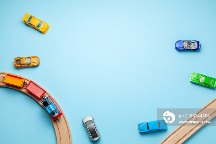 Children’s railway with wooden rails and cars on a blue background, top view. Copy space for text.