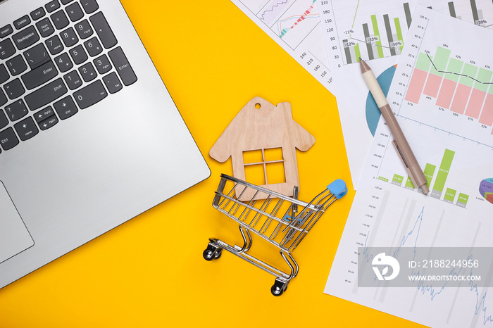 Laptop, shopping trolley, figure house with graphs and charts on a yellow background. Business plan, financial analytics, statistics. Top view