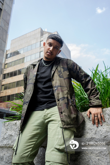 Man wearing camouflage jacket and cargo pants,looking at camera