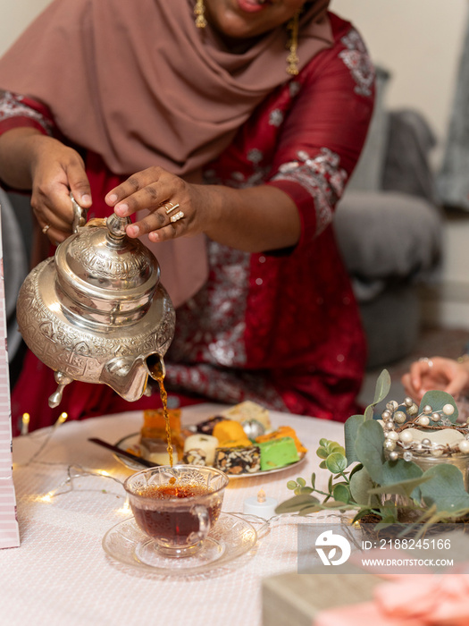 Woman pouring tea during Ramadan celebration at home