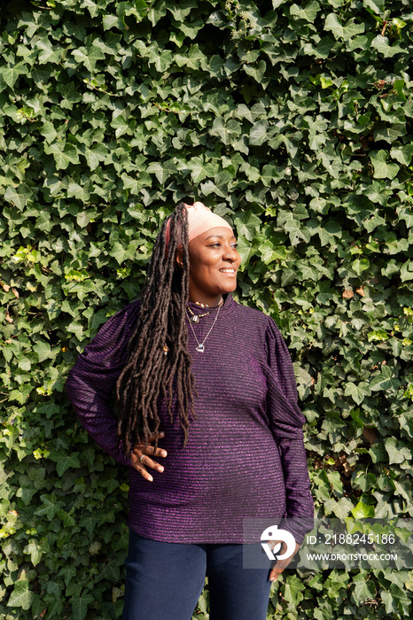 Portrait of beautiful woman with dreadlocks in front of ivy wall