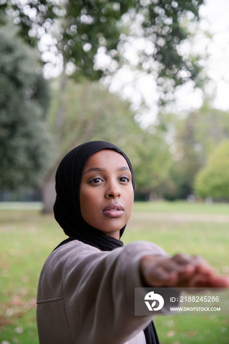 Portrait of woman in hijab in yoga warrior pose in park