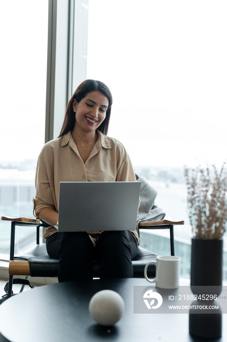 Businesswoman with laptop sitting in office lobby