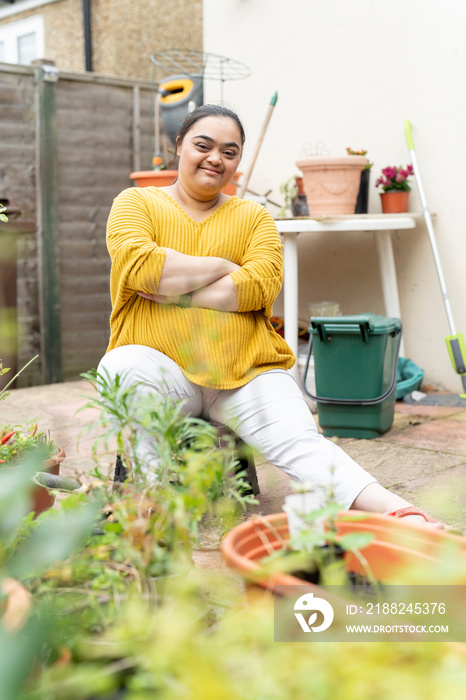 Portrait of young woman with down syndrome planting flowers in garden