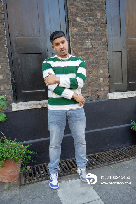 Man wearing striped sweatshirt and jeans looking at camera