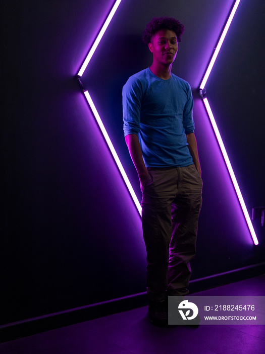 Portrait of young man against wall with neon lights