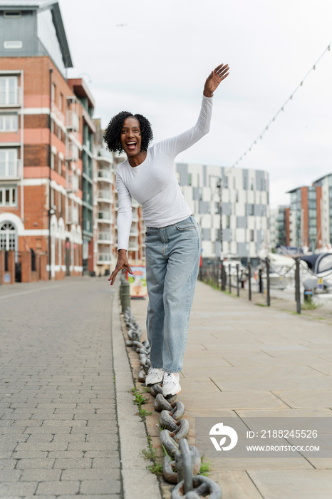 Smiling woman balancing on chain link in city