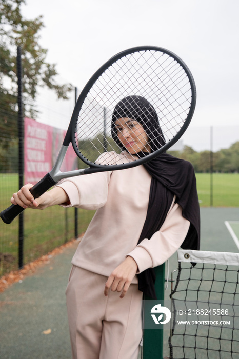 Portrait of woman in hijab holding tennis racket at tennis court