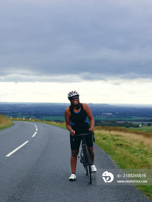 Smiling female cyclist on country road