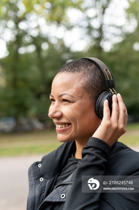 Smiling woman with headphones in park