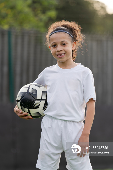 Portrait of girl (6-7) wearing soccer uniform holding ball