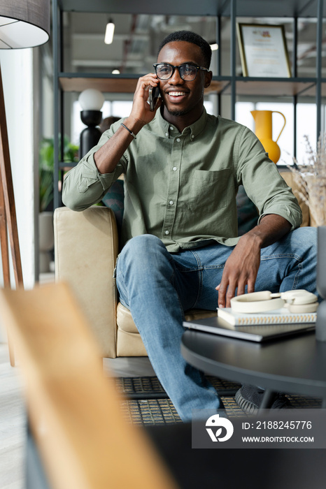 Young man with smartphone sitting in office lounge