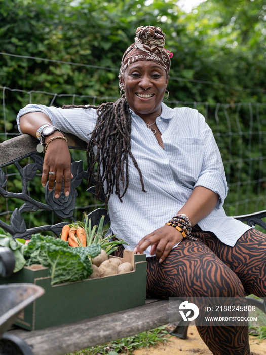 Portrait of smiling woman resting on bench after working in garden