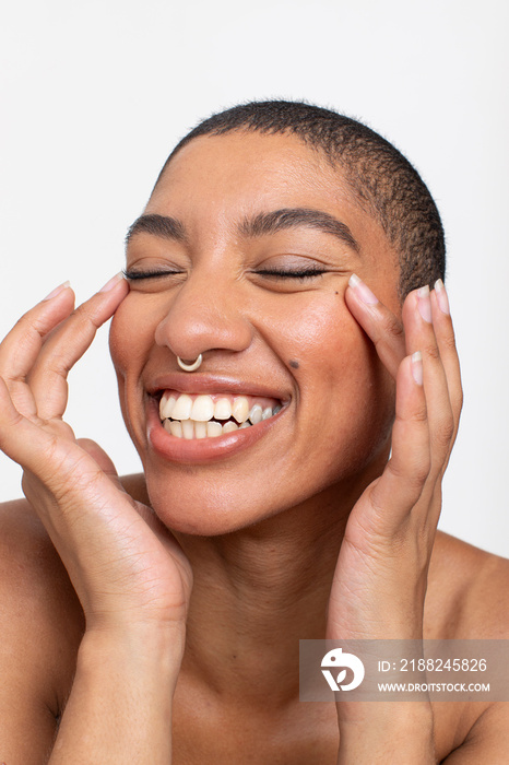 Studio portrait of smiling woman with nose ring touching face